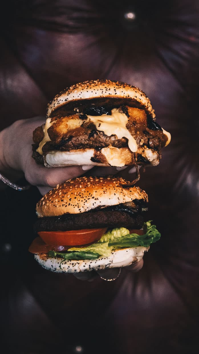 Two smashed burgers stacked with melted cheese and sauce on poppy seed buns at The Bellman